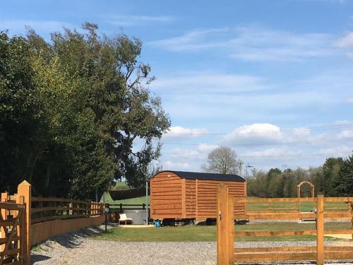 a large woodenshed in a field next to a fence at Shepherds Haven in Draycott in the Moors