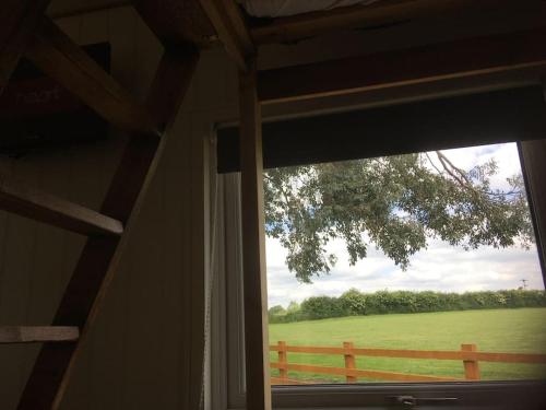 a window with a view of a field and a fence at Shepherds Haven in Draycott in the Moors