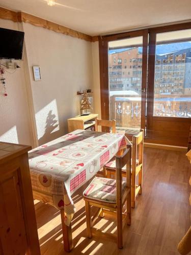 une pièce avec une table, des chaises et une fenêtre dans l'établissement Centre village 6 personnes, à Val Thorens