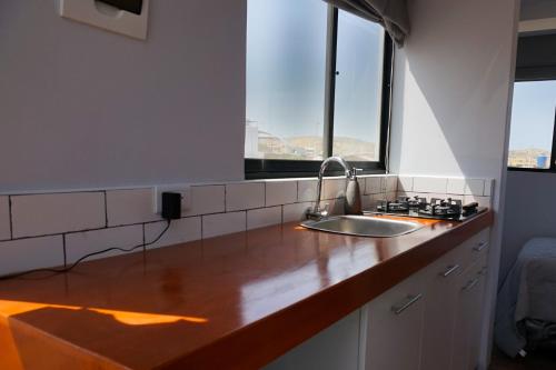 a kitchen counter with a sink and two windows at Che Lobitos in Lobitos