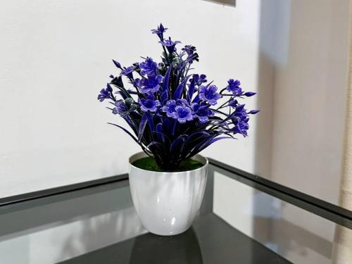 a white vase with blue flowers sitting on a table at Stylish Studio Dave Apt Depok with Pool, WiFi, Netflix by 2ndHome in Pondoktjina Tiga