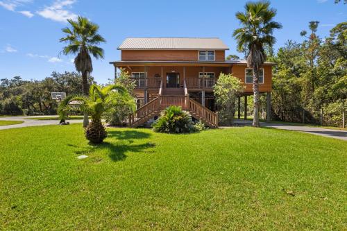a house with a lawn and palm trees at Pool Retreat Waterfront 6 Bedroom Boat Ramp Game Room Pass Christian Home in Pass Christian