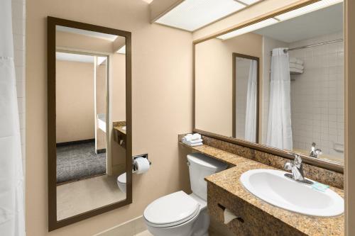 a bathroom with a toilet and a sink and a mirror at Anaheim Portofino Inn & Suites in Anaheim