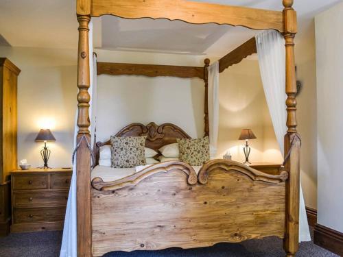 a bedroom with a wooden canopy bed with two lamps at Eastfield Cottage free parking and EV charger in Leven