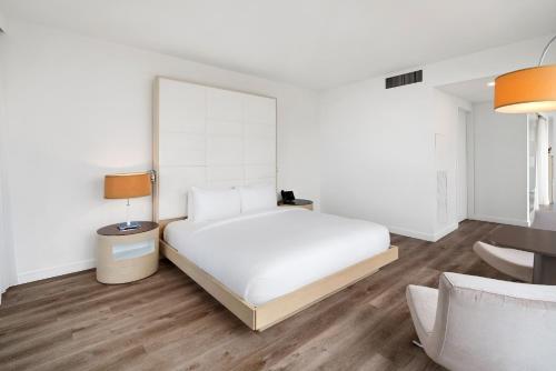 a white bedroom with a bed and a table and a chair at The Grayson Hotel Miami Downtown in Miami