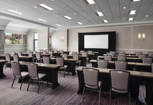 a conference room with tables and chairs and a screen at Hanover Marriott in Whippany