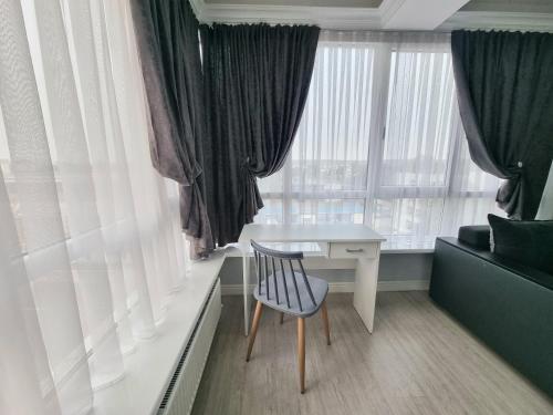 Una habitación con un escritorio y una silla junto a una ventana. en Botanical Garden Park Apartment, en Chişinău