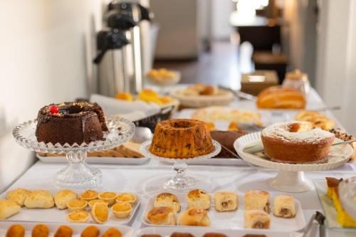 a table filled with cakes and pastries on plates at Pousada Solar da Inconfidência - fácil acesso a Praça Tiradentes in Ouro Preto