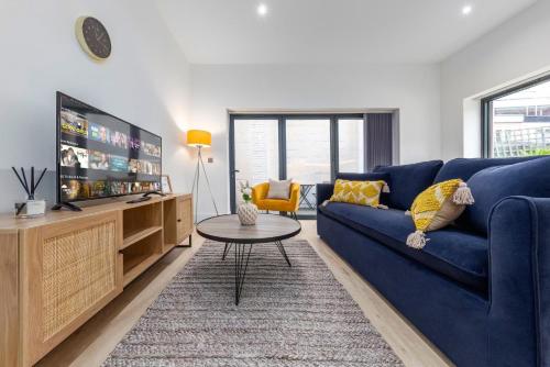 a living room with a blue couch and a tv at Sercasa - Kingston upon Thames in Kingston upon Thames