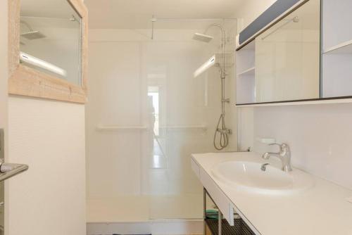 une salle de bain blanche avec un lavabo et une douche dans l'établissement Sky baulois - Exceptionnel - vue mer - parking, à La Baule
