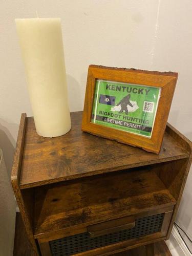 a candle and a picture on a wooden table at Sleeps 5-6 Near RRG-Hot Tub-Nice Sunrise-Quiet in Beattyville