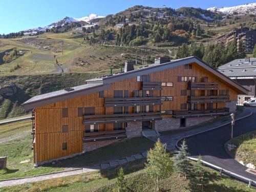 un bâtiment sur une colline avec des montagnes en arrière-plan dans l'établissement Studio skis aux pieds, bien équipé avec Wi-Fi – Les Allues - FR-1-182-42, à Méribel