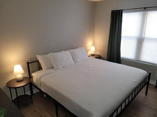a bedroom with a large white bed with two lamps at Aksarben Gem-Easy access to I-80 in Omaha