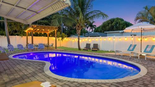 a swimming pool in a yard with chairs and an umbrella at Sunset Oasis with Movie Theatre, Heated Pool & Game Room in Pompano Beach