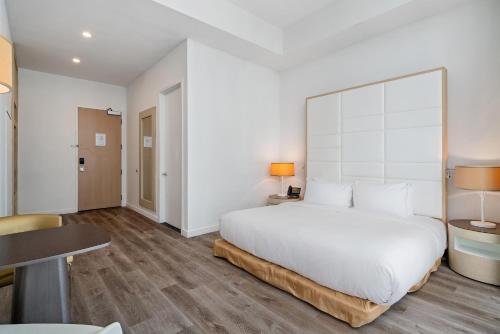 a bedroom with a large white bed and a table at The Grayson Hotel Miami Downtown in Miami