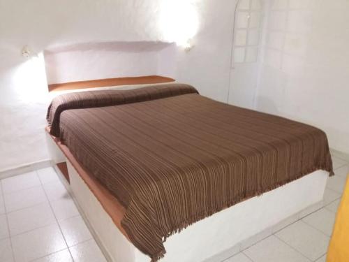 a bed with a brown blanket on top of it at Casa cueva primera línea playa in Gáldar