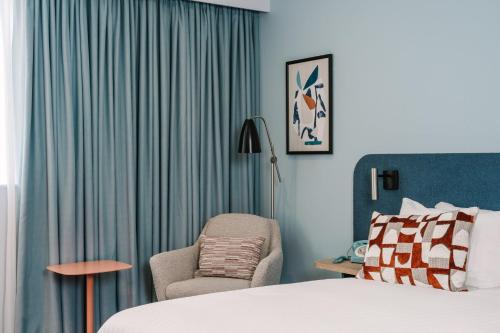 a hotel room with a bed and a chair at voco Winchester Hotel & Spa by IHG in Winchester