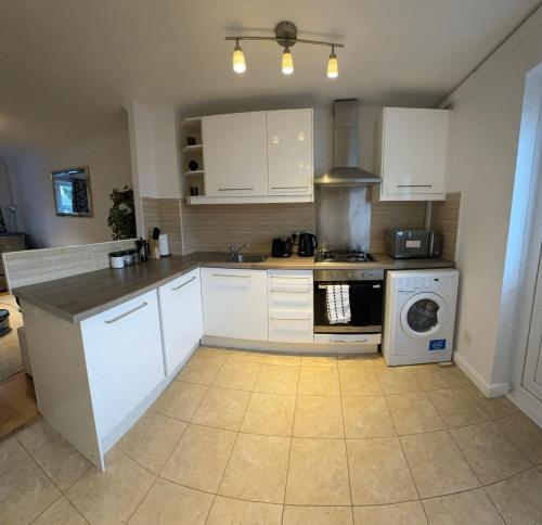 a kitchen with white cabinets and a stove top oven at 2 Bed House near Canary Wharf in London