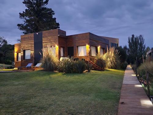 a wooden house with a lawn in front of it at Casa Cortés Golf - Boutique in Sierra de la Ventana