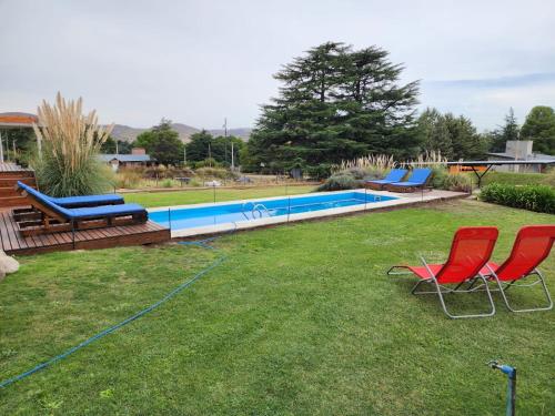 a yard with two chairs and a swimming pool at Casa Cortés Golf - Boutique in Sierra de la Ventana