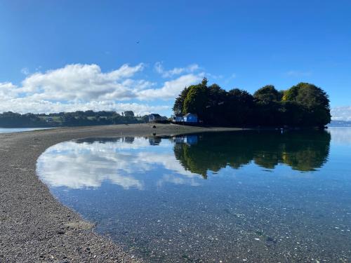 a beach with a reflection of the sky in the water at Cabaña en tu propia Isla in Chonchi