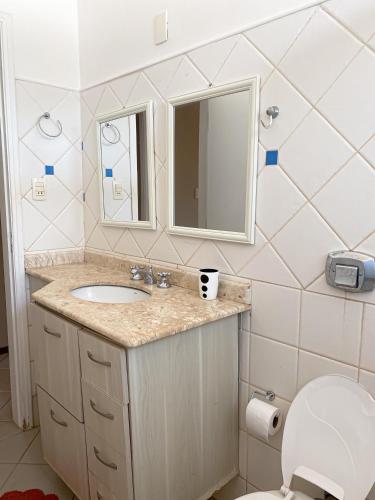 a bathroom with a sink and a mirror and a toilet at Chacara espetacular em condomínio fechado in Ribeirão Preto