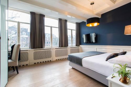 a bedroom with blue walls and a bed and windows at Grand Canal Boutique Hotel in Amsterdam