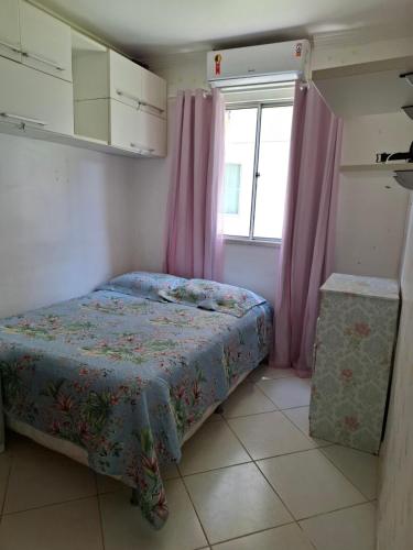 a bedroom with a bed and a window with pink curtains at Ilhéus Temporada in Ilhéus