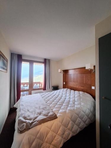 une chambre avec un grand lit avec une grande fenêtre dans l'établissement Résidence La Marelle et Le Rami - maeva Home - Appartement au pied des pistes 3 pièces 7 personnes - Sélection - super Home MAE-3881, à La Plagne Tarentaise