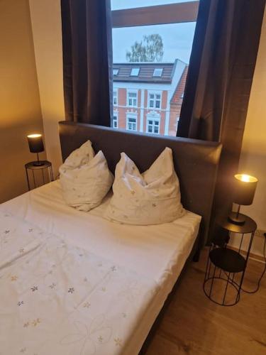 a bed with two pillows in front of a window at Helle 3 Zimmer Wohnung im Harz in Halberstadt