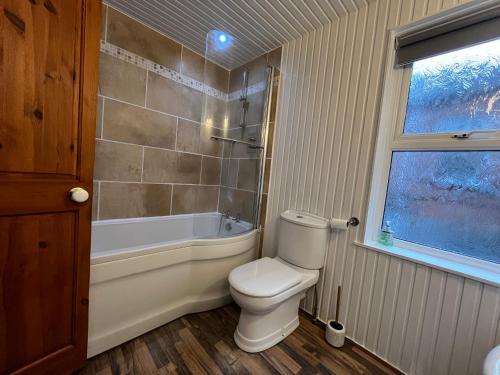 a bathroom with a toilet and a tub and a window at Gr8 Hostel at The Mount in Belfast