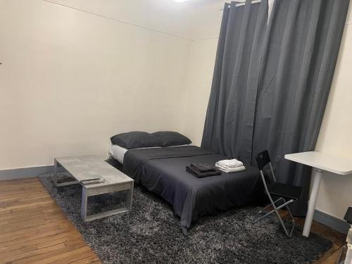 - une chambre avec un lit, une table et des rideaux dans l'établissement Studio proche Paris, proche meteo 4,13, à Montrouge