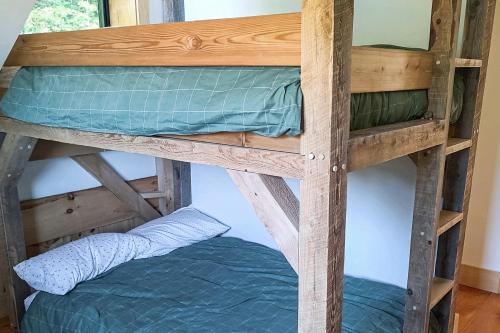 a wooden bunk bed with a blue pillow on the bottom level at The Hollow in Plymouth