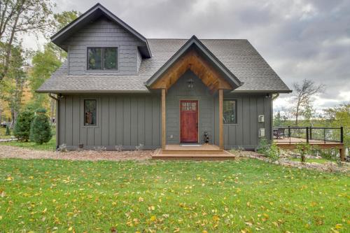 a gray house with a red door in a yard at Pequot Lakes Retreat with Beach and Fire Pit! in Pequot Lakes