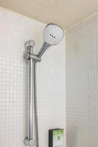 une douche avec pommeau de douche dans une salle de bain dans l'établissement Campanile NATURE - Paris Ouest Gennevilliers Port, à Gennevilliers