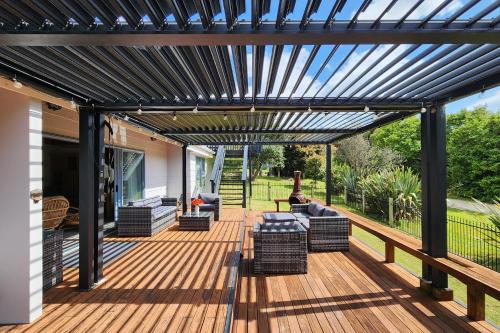 a wooden deck with a black pergola at FlipFlop Inn Hahei Beach in Hahei
