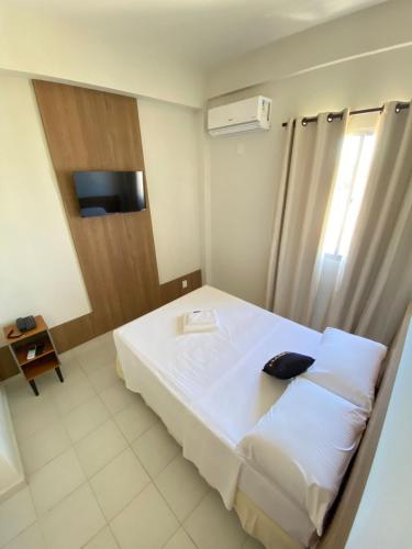 a bedroom with a large white bed and a television at NORTH HOTEIS in Montes Claros