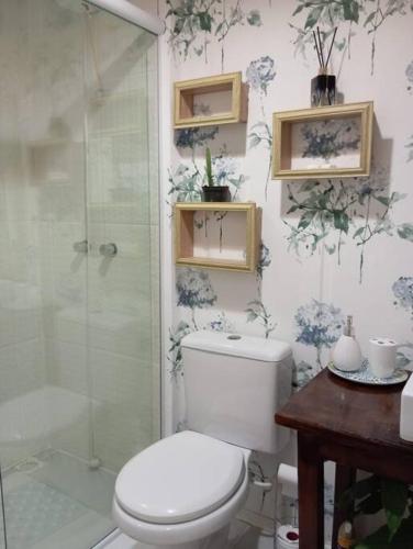 a bathroom with a toilet and a glass shower at Condomínio Villa de Portugal Suíte Por do Sol in São Francisco do Sul