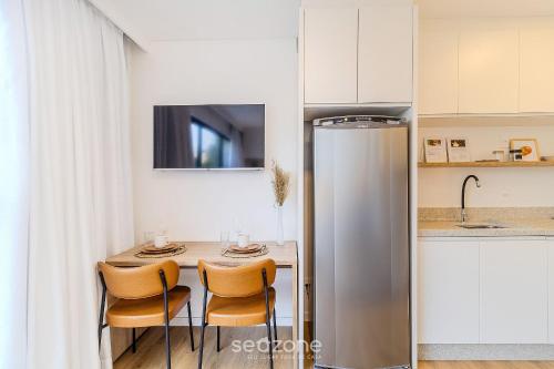 a kitchen with a table with chairs and a refrigerator at RUP - Studios Equipados em Prédio com Piscina in Blumenau