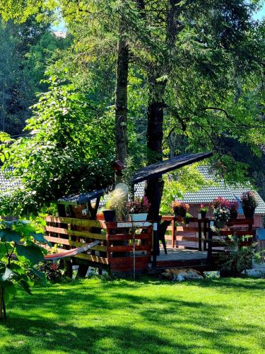 a park bench and a gazebo in the grass at Casuta dintre brazi - Valea Doftanei - 2 camere in Valea Doftanei