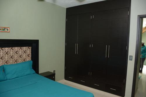 a bedroom with a blue bed and black cabinets at Comfort House La Herradura in Arandas