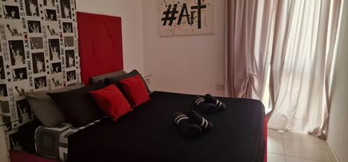 a bedroom with a black bed with red pillows at PACEVILLE St Julians Apartments in St Julian's