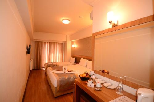 a hotel room with two beds and a desk at Grand Anzac Hotel in Çanakkale