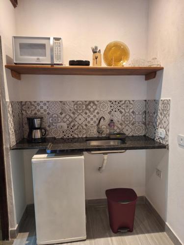 a small kitchen with a microwave on a shelf at Pousada Schueng in Trindade