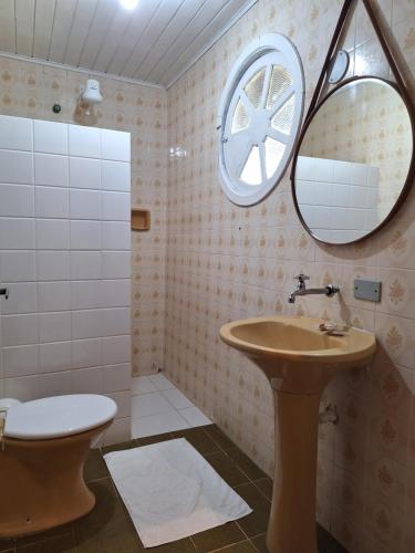 a bathroom with a sink and a toilet and a mirror at Pousada Schueng in Trindade