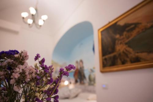 a vase filled with purple flowers next to a painting at ApartHotel Antica Repubblica in Amalfi center at 100mt from the sea in Amalfi