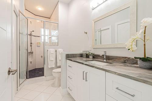 une salle de bain blanche avec un lavabo et une douche dans l'établissement Breathtaking 6BD Riverfront Mansion w Pool, à Cape Coral