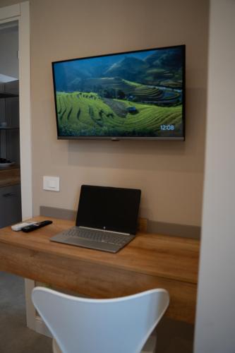 a laptop on a wooden desk with a television on the wall at Freedom in SantʼAntonio Abate