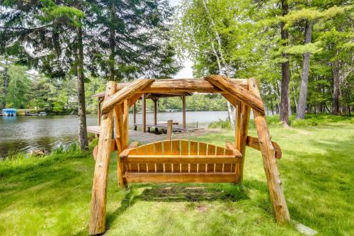 a wooden gazebo in the grass next to a lake at Waterfront Eagle River Home with Dock and Fire Pit! in Eagle River