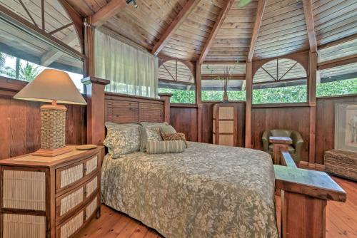 a bedroom with a bed in a room with wooden walls at Tropical Cabana with Deck, Hot Tub and Lush Scenery! in Keaau
